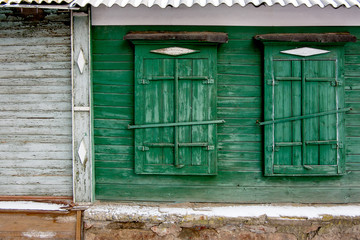 Two green old wooden window in a painted wall.