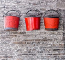 The old red metal buckets for decoration on the brick wall