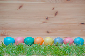 happy easter eggs pastel colored with grass on the wooden