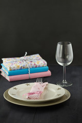  Table setting with stack of books on dark wooden table