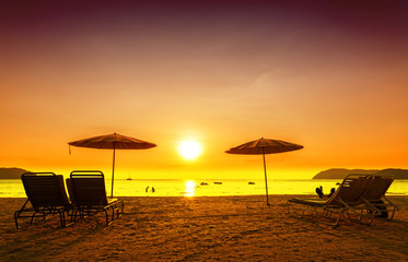 Retro filtered picture of beach chairs and umbrellas at sunset.