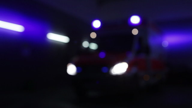 Defocused shot of an amublance at night. Blue light and siren