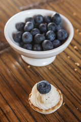 Cookingh sweet tartlets filled with cream and  blueberry on wood