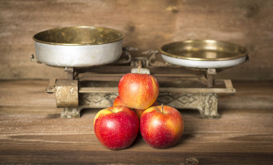 Old balance with apples on wooden background
