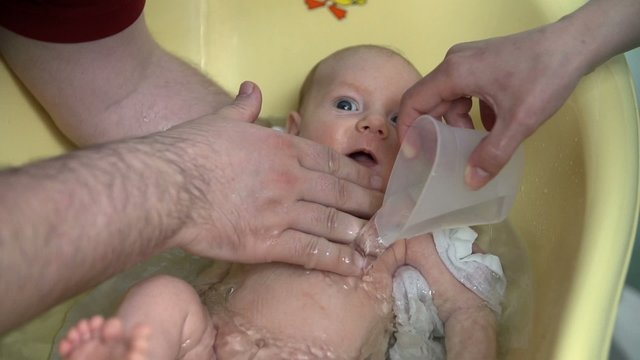 Parents giving their baby a bath 
