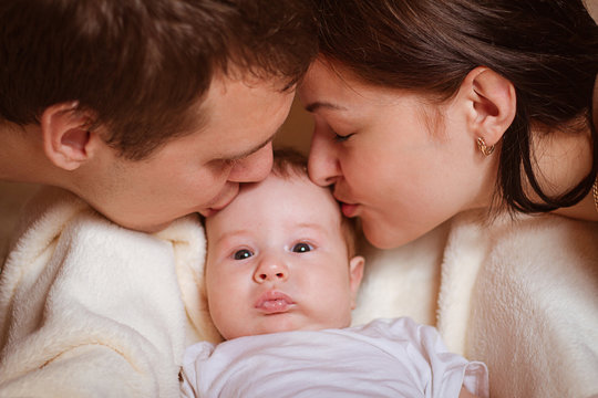 happy family. happy young parents kissing their baby
