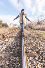 Beautiful Young Woman Walking in Balance on Railway Tracks. The