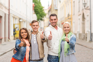 group of smiling friends showing thumbs up