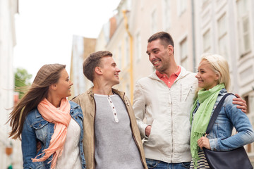 group of smiling friends walking in the city