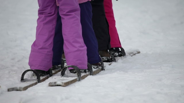 legs of kids trying to synchronize walking on wooden skis
