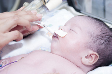 Portrait of newborn baby and hand inside incubator