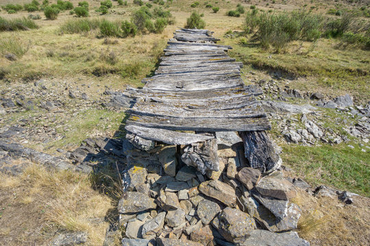 Top of bridge made with wood and stones, dried up stream
