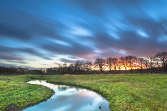 Long Exposue Sunset with Blurred Clouds over River Landscape