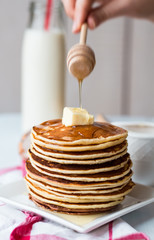 pile of Pancake with butter, honey sauce add,  hands