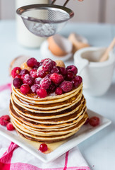 Pancake with cranberries, raspberries and powdered sugar, hands
