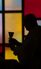 priest lifting chalice  silhouette