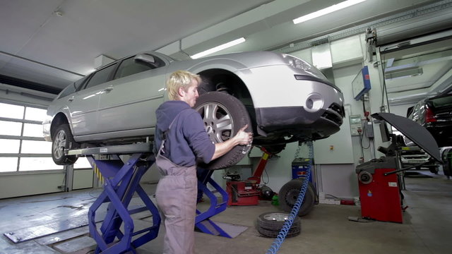 Blond mechanic removing tires for straightening