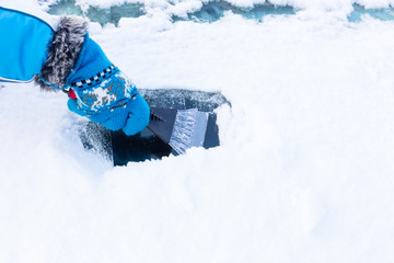 Hand in glove scratching snow from windshield