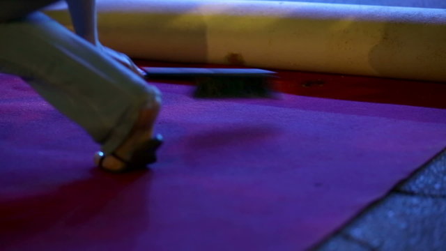 Woman is cleaning the red carpet squating in her jeans