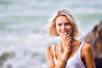 Beautiful young blonde woman posing outdoor at the rocky sea sho