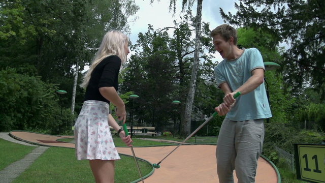 Man and women sword fighting with golf clubs slow motion
