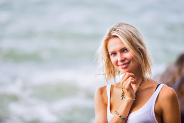 Beautiful young blonde woman posing outdoor at the rocky sea sho