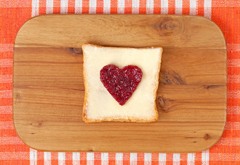 Slice of wholewheat toast with red jam in the shape of heart