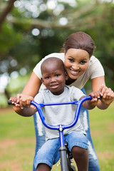 Obraz premium african mother teaching her little son to ride a bike