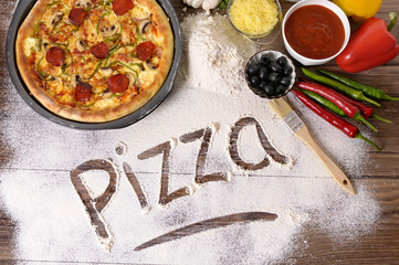 The word Pizza written in flour with various ingredients making cooking preparing photo