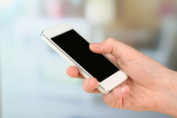 Hand using smart mobile phone on light blurred background