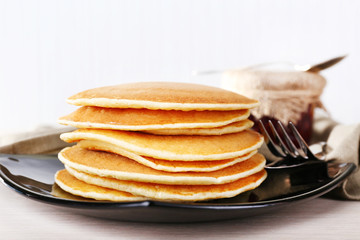 Stack of pancakes on plate on table and light background