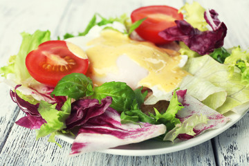 Toast with egg Benedict and tomato on plate on wooden table