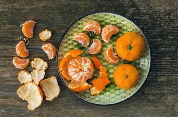 A plate of fresh ripe juicy mandarins over a rough wood backgrou