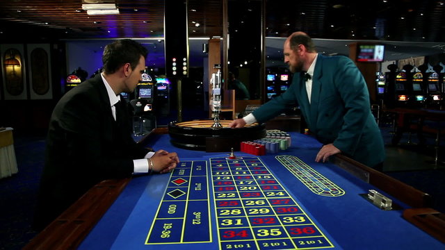 Young and attractive man playing roulette in casino