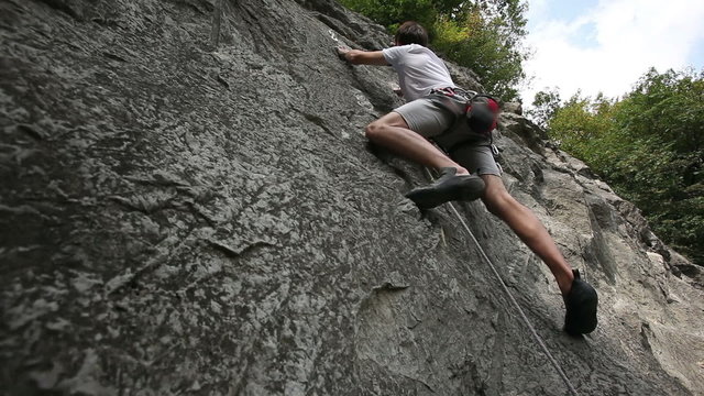HD1080p: Man rock climbing in nature shot from below