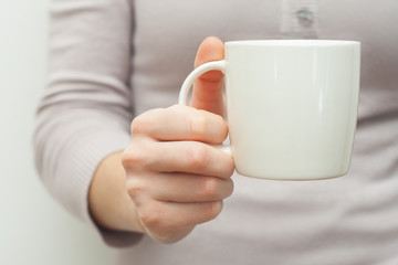 Woman hands holding white cup of tea or coffe