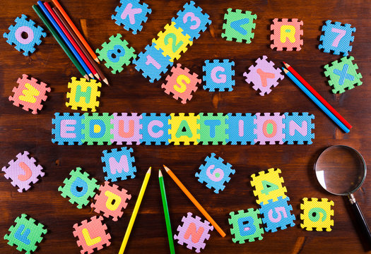 puzzle letters with pencils on wooden background