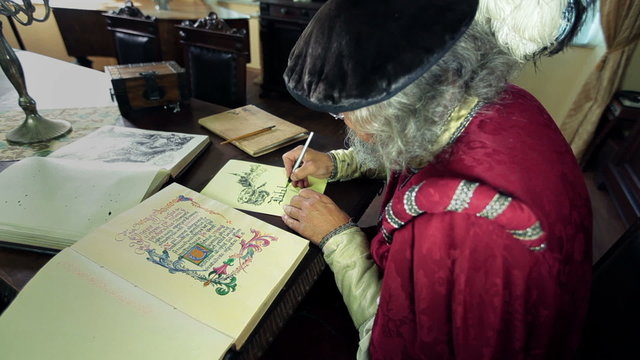 Writer in medieval clothes writing in caligraphy