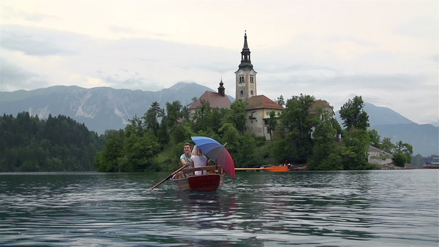 Man and woman in rowboat traveling to Bled church
