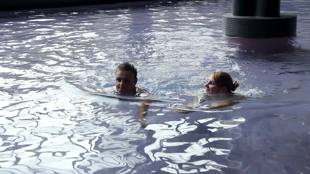 young couple in pool chit chatting