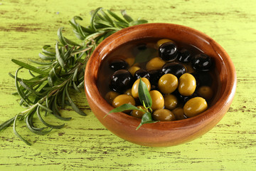 Black and green olives with leaves in bowl