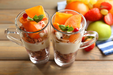 Healthy layered dessert with muesli and fruits on table