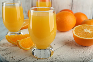 Glass of orange juice with slices on color wooden background