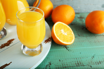 Glass of orange juice with slices on color wooden background