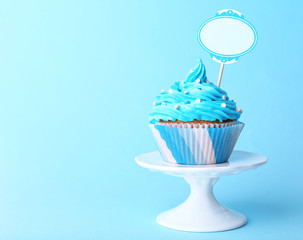 Delicious cupcake with inscription on blue background