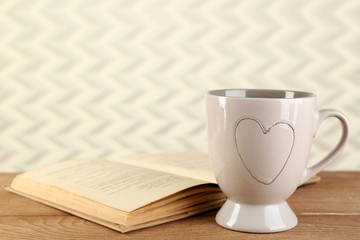 Cup of tea and book on table, on light background