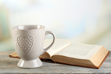 Cup of tea and book on table, on light background