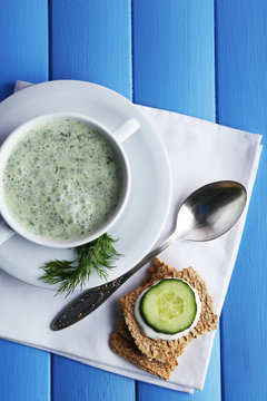 Cucumber soup in bowl on color wooden planks background