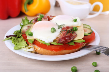 Sandwich with poached eggs, bacon and vegetables