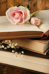 Books with flowers on wooden background